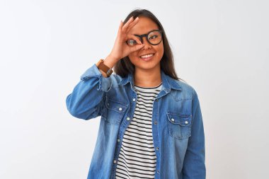 Kot gömlek ve gözlük takan Çinli genç bir kadın izole edilmiş beyaz arka planda el hareketleriyle gülümsüyor ve mutlu yüzle parmaklarının arasından bakıyor..