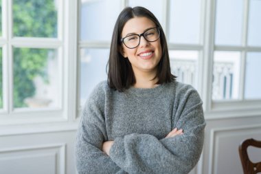 Güneşli bir günde evde rahat duran neşeli gülümseyen gözlüklü genç güzel kadın