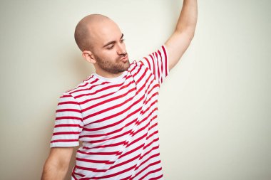 Sakallı genç kel adam beyaz izole arka plan üzerinde rahat çizgili kırmızı t-shirt giyen dans mutlu ve neşeli, rahat ve kendinden emin müzik dinleme hareketli gülümseyerek