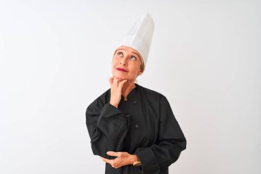 Orta yaş şef kadın üniforma ve şapka giyen çene üzerinde el ile izole beyaz arka plan üzerinde duran soru, dalgın ifade düşünme. Düşünceli bir yüzle gülümsüyor. Şüphe kavramı.