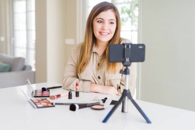 Beautiful young influencer woman recording make up video tutorial with a happy and cool smile on face. Lucky person.