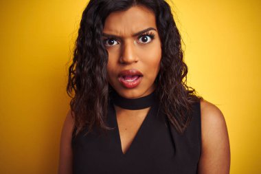 Izole sarı arka plan üzerinde siyah t-shirt giyen transseksüel transseksüel kadın sürpriz bir yüz ile şok korkmuş, korku ifade korku ve heyecanlı