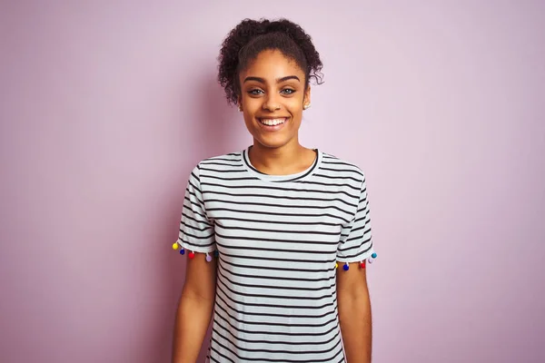 African american woman wearing navy striped t-shirt standing over isolated pink background with a happy and cool smile on face. Lucky person.