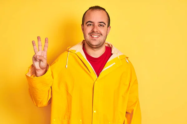 Mladý Muž Pláštěnce Stojí Nad Izolovaným Žlutým Pozadím Ukazuje Ukazuje — Stock fotografie