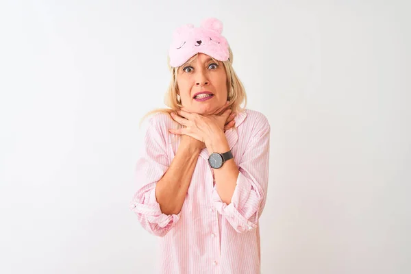 Middle age woman wearing sleep mask and pajama over isolated white background shouting and suffocate because painful strangle. Health problem. Asphyxiate and suicide concept.