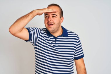 Sıradan çizgili polo giyen genç adam izole edilmiş beyaz arka planda çok mutlu ve tebessüm ediyor. Konsept aranıyor.