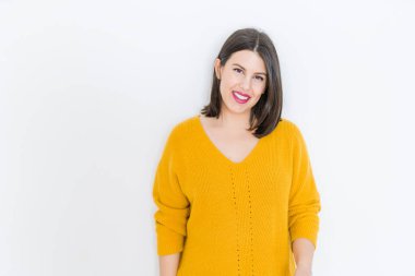 Güzel esmer genç kadın kendine güvenen ve neşeli rahat sarı kazak giyen izole beyaz arka plan üzerinde gülümseyen