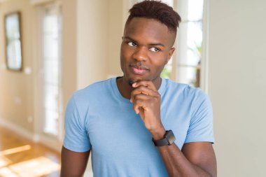 Yakışıklı afro-amerikan adam çene üzerinde el ile rahat t-shirt giyen soru, dalgın ifade düşünme. Düşünceli bir yüzle gülümsüyor. Şüphe kavramı.