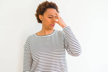 Genç güzel afro-amerikan kadın beyaz arka plan üzerinde çizgili kazak giyen bir şey kokulu ve, dayanılmaz koku, burun parmakları ile nefes tutarak kokuyor. Kötü kokular kavramı.