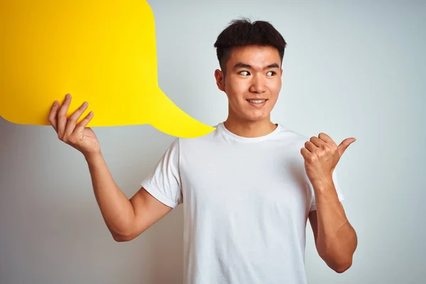 亚洲华人男子拿着演讲泡泡站在孤立的白色背景上指着 用大拇指向一边露出开心的脸微笑 — 图库照片