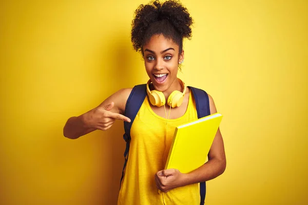 Afro Kvinna Med Ryggsäck Och Hörlurar Håller Anteckningsbok Över Isolerad — Stockfoto