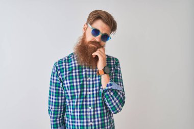 Genç kızıl İrlandalı adam izole beyaz arka plan üzerinde rahat gömlek ve güneş gözlüğü giyen yorgun görünümlü ve çapraz kolları ile depresyon sorunları ile sıkılmış düşünme.
