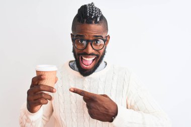 Örgü örüp kahve içen Afrikalı Amerikalı bir adam izole edilmiş beyaz arka planda mutlu bir şekilde el ve parmak göstererek kahveyi götürür.
