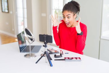 Genç afro-Amerikan influencer kadın kayıt öğretici deli kutluyor makyaj ve silah kaldırdı ve açık gözleri heyecan çığlık ile başarı için hayran. Kazanan kavramı