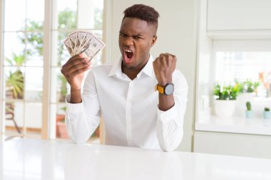 Afro-amerikan adam elli dolar banka banknotları tutan kızgın ve sinirli öfke, deli ve yükseltilmiş el, öfke kavramı ile bağırıyor