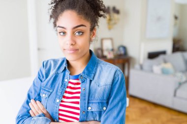 Yüzünde ciddi ifade ile rahat rahat denim ceket giyen afro saçlı güzel genç Afro-Amerikan kadın. Basit ve çapraz silah ile doğal