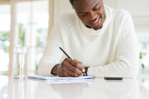 Close-up van Afrikaanse man het schrijven van een notitie op een papier glimlachend Confid — Stockfoto