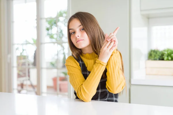 年轻美丽的金发女孩穿着休闲黄色毛衣在家里拿着象征性的枪与手势 玩杀人射击武器 愤怒的脸 — 图库照片