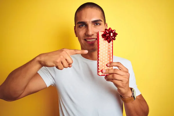 Ung Kaukasier Man Håller Födelsedagspresent Över Gul Isolerad Bakgrund Mycket — Stockfoto