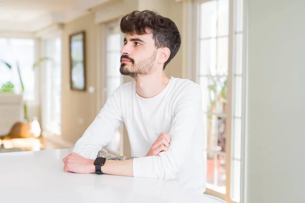 Hombre Joven Con Camisa Casual Sentado Mesa Blanca Mirando Lado —  Fotos de Stock