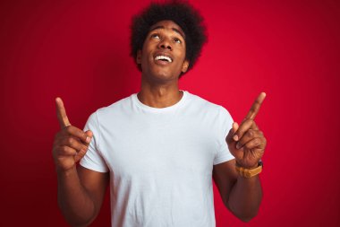 Beyaz saçlı beyaz saçlı genç amerikalı adam izole kırmızı arka plan üzerinde duran şaşırmış ve şaşırmış yukarı bakarak ve parmakları ile işaret ve kolları kaldırdı.