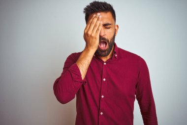 Izole gri arka plan üzerinde duran kırmızı zarif gömlek giyen genç hintli adam el ile yarım yüz, göz ve ağız kapsayan yorgun Esneme. Yüz acı içinde acıyor.