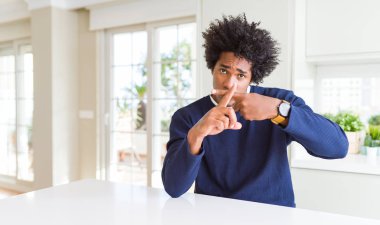 Genç afro-amerikan adam evde oturan rahat kazak giyen Reddi ifade olumsuz işaret yapıyor parmakları geçiş