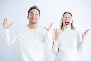 Genç güzel çift rahat t-shirt izole beyaz arka plan üzerinde ayakta giyen deli ve silah kaldırdı ve kapalı gözleri heyecan çığlık ile başarı için deli kutluyor. Kazanan kavramı