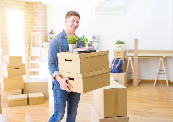 Joven Guapo Sonriendo Feliz Mudándose Nuevo Hogar Muy Emocionado Sosteniendo —  Fotos de Stock