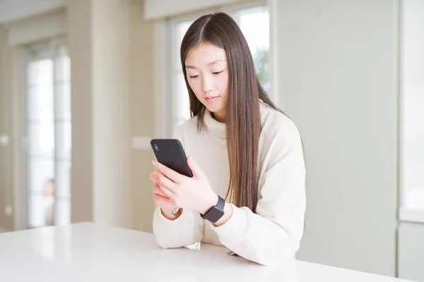 漂亮的亚洲女人用智能手机带着自信的表情脸上挂着严肃的表情 — 图库照片