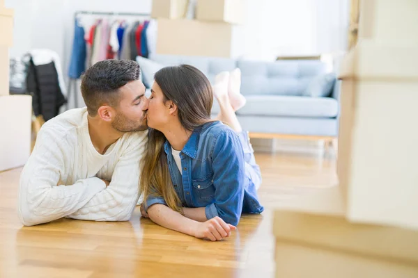 Junges schönes Paar, lächelnd auf dem Boden des neuen Hauses liegend — Stockfoto