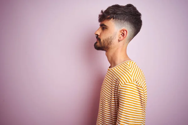 줄무늬 티셔츠를 옆으로 보이는 고립된 분홍색 서있는 문신을 남자는 자신감있는 — 스톡 사진