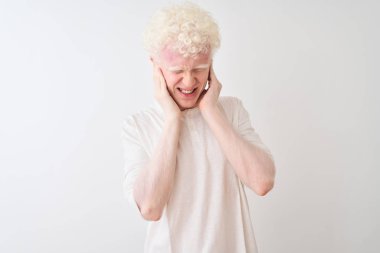 Genç albino sarışın adam yüksek sesle müzik sesi için rahatsız ifade ile parmakları ile kulakları kapsayan izole beyaz arka plan üzerinde duran rahat t-shirt giyiyor. Sağır kavramı.