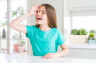 Güzel genç kız kız yeşil t-shirt giyen el gülümseyerek ok jest yapıyor, mutlu yüz ile parmaklardan bakan göz.