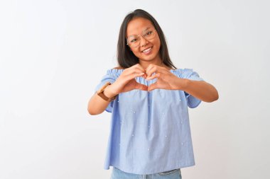 Mavi tişört ve gözlük takan Çinli genç bir kadın izole edilmiş beyaz arka planda aşkla gülümsüyor ve elleriyle kalp sembolü yapıyor. Romantik konsept.