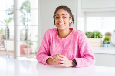 Afro saçlı güzel afro-amerikan kadın rahat pembe kazak giyen Eller birlikte ve parmakları gülümseyerek rahat ve neşeli geçti. Başarı ve iyimser