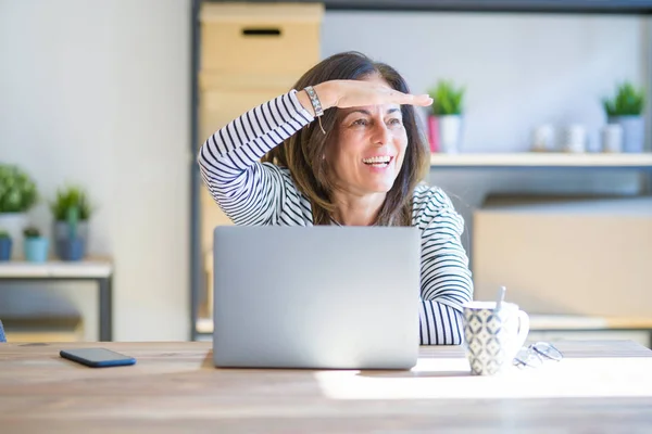 坐在桌旁工作的女中年妇女使用电脑笔记本电脑工作非常高兴 面带微笑地看着远方的手头 搜索概念 — 图库照片