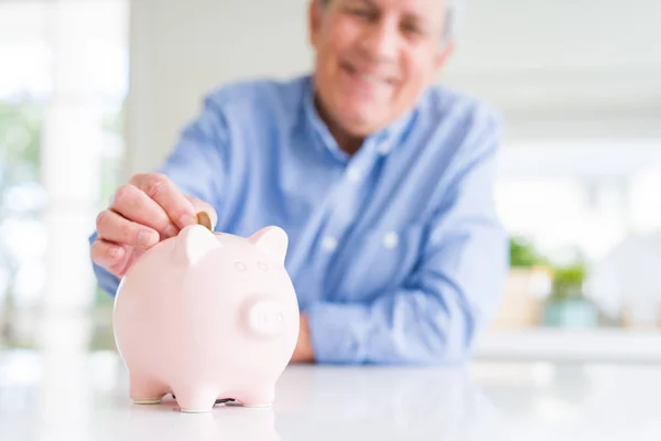 Man putting a coin inside piggy bank as savings smiling confiden