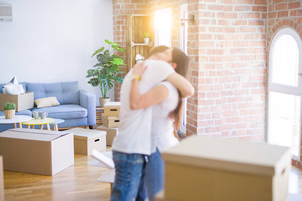 Молодая красивая пара обнимается в новом доме вокруг картонных коробок
