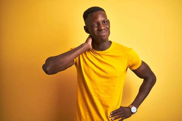 年轻的非洲裔美国男子穿着休闲T恤站在孤立的黄色背景遭受颈部疼痛伤害 用手触摸颈部 肌肉疼痛 — 图库照片