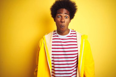 Afro saçlı afro saçlı afro-amerikan adam izole sarı arka plan üzerinde dudaklar, deli ve komik jest ile balık yüz yapma ayakta yağmurluk giyiyor. Komik ifade.