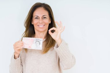 25 kilo banknot tutan orta yaşlı bir kadın izole edilmiş arka planda tamam işareti yapıyor, mükemmel bir sembol.