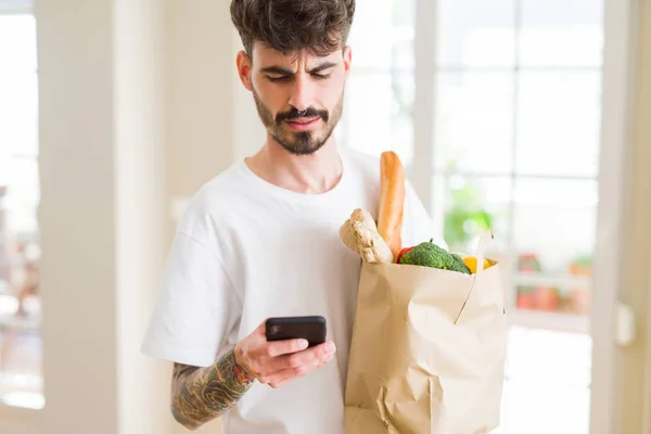 Jeune homme beau tenant un sac en papier plein d'épicerie fraîche a — Photo