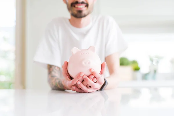 Close-up de homem segurando porquinho banco, economizando dinheiro para o investimento — Fotografia de Stock