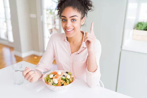 健康的なパスタサラダを食べる若いアフリカ系アメリカ人女性は 幸せな顔で指を指すアイデアや質問に驚きました ナンバーワン — ストック写真