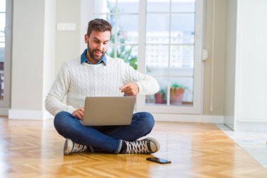 Yakışıklı adam bilgisayar laptop kullanarak çalışma giyen çok mutlu el ve parmak ile işaret