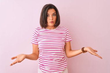 İzole edilmiş pembe arka planda duran çizgili t-shirt giyen genç ve güzel bir kadın..