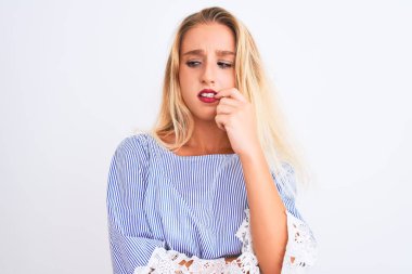 Genç güzel kadın zarif mavi t-shirt izole beyaz arka plan üzerinde duran giyen stresli ve ağız tırnak ısırma elleri ile sinir görünümlü. Anksiyete sorunu.