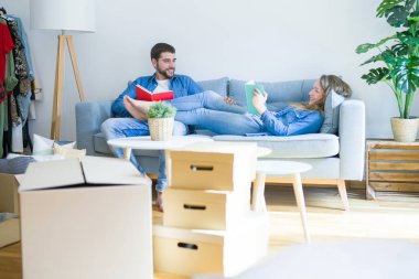Genç çift kanepede bir kitap okuma rahatlatıcı, yeni bir eve hareket için bir mola alarak