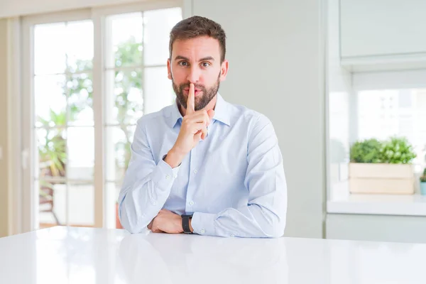 Handsome business man asking to be quiet with finger on lips. Silence and secret concept.